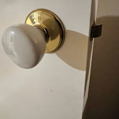 Close-up of a newly installed passage knob with a brass base and ceramic knob on a white door.