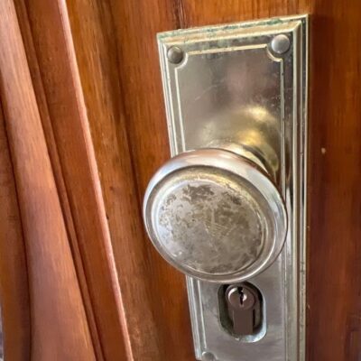 Close-up view of a Gainsborough Trilock installed on a wooden door, featuring a round doorknob and keyhole.