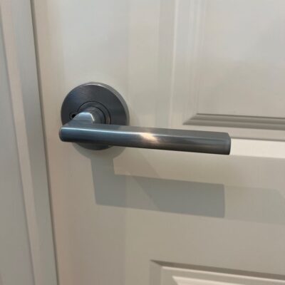 Close-up view of a metallic lever door handle on a white door.