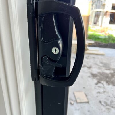 Close-up of a newly installed sliding door lock with a keyhole in a residential setting.