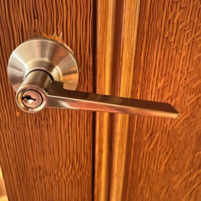 Close-up of a metallic door handle with a keyhole on a textured wooden door.