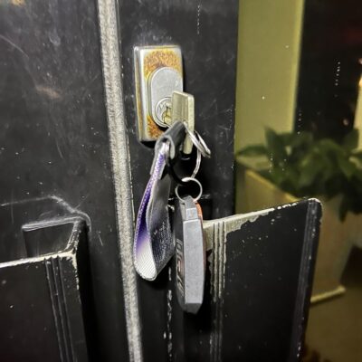 Key stuck in a rusted lock on an office door with a keychain attached