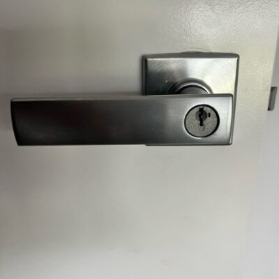 Close-up of a newly installed modern metallic door handle with keyhole on a white door.