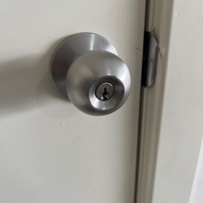 Close-up of a stainless steel door knob with keyhole on a white door.