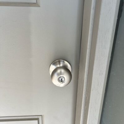 Close-up view of a metallic door knob with a keyhole on a light-colored wooden door.