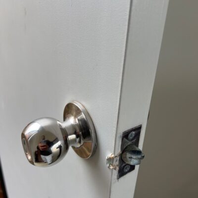 Close-up of new deadbolt installation on a white door with a metallic doorknob.