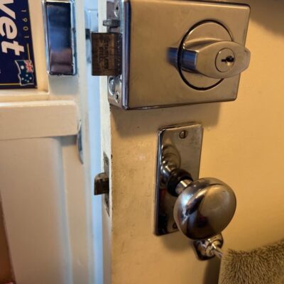 Close-up view of a door with a new metallic deadbolt lock and round door knob.