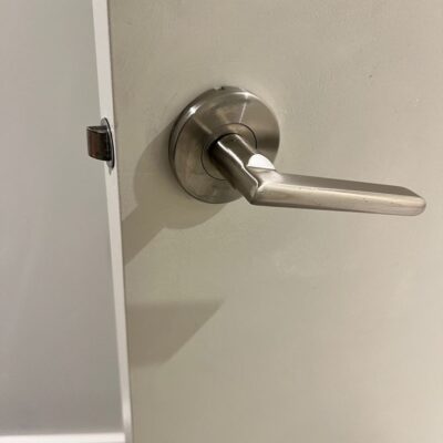 Close-up of a newly installed brushed metal privacy door handle on a white door.
