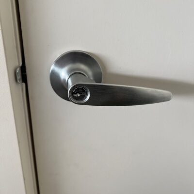 Close-up of a metal door handle with a keyhole on a white door