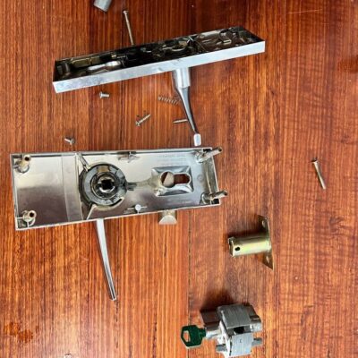 Disassembled lock handle parts spread out on a wooden surface.