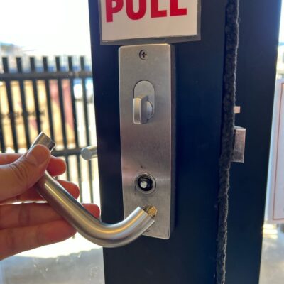 Hand holding a broken door handle next to a lock with a "PULL" sign above it.