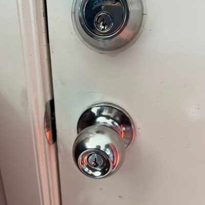 Newly installed chrome Gainsborough deadbolt and knobset on a white door.